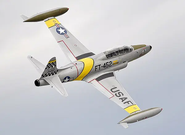 A white and yellow colored plane flying towards right